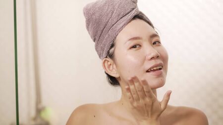 home lifestyle portrait of young beautiful and happy Asian Chinese woman with head wrapped in towel smiling fresh and cheerful after taking shower enjoying morning routine and hygieneの写真素材