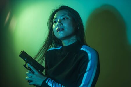 cinematic portrait of young attractive and dangerous special agent woman spy or Asian Korean mobster girl holding handgun pointing the gun fierce in Hollywood movie styleの写真素材