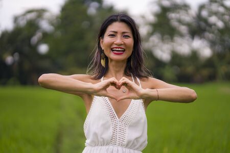outdoors holidays portrait of attractive and happy middle aged Asian Chinese woman in white dress...