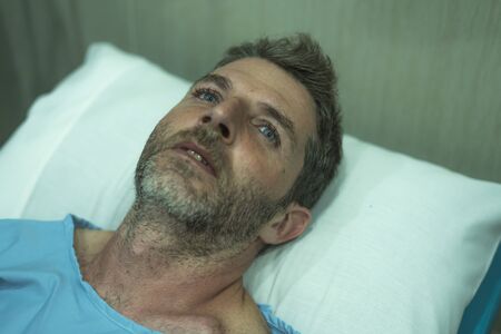 scared and worried man hospitalized - close up portrait of attractive injured man lying on hospital...