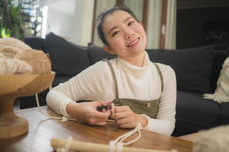 Asian girl enjoying macrame handcraft hobby - young happy and pretty Chinese at home doing macramŽ...