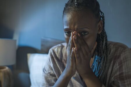 young sad and depressed black afro  woman on bed at home unhappy and sleepless at night feeling overwhelmed suffering depression problem and insomniaの写真素材