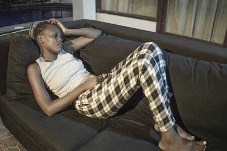 young afro American woman suffering depression - sad and depressed black teenager girl in pain at home sofa couch feeling overwhelmed and emotional crying lonely in the darkの写真素材