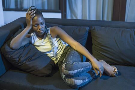 young afro American woman suffering depression - sad and depressed black teenager girl in pain at home sofa couch feeling overwhelmed and emotional crying lonely in the darkの写真素材