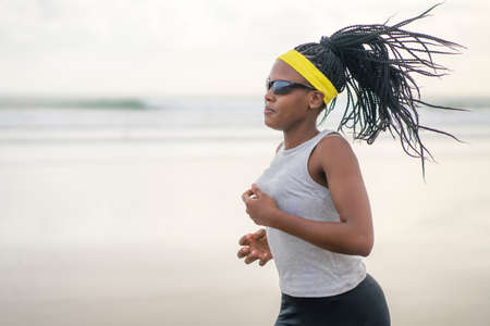 post quarantine runner girl enjoying outdoors workout - young attractive and fit black African American woman running wearing face mask in new normal sport practice concept and healthy lifestyleの写真素材