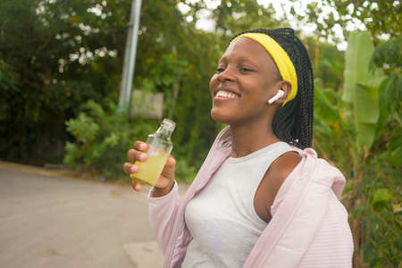 runner girl lifestyle portrait - young attractive and fit black afro American woman looking away happy and satisfied after outdoors running workout  at countryside roadの写真素材