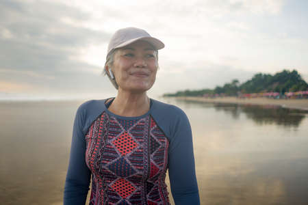 portrait of fit and happy middle aged woman after beach running workout - 40s or 50s attractive...