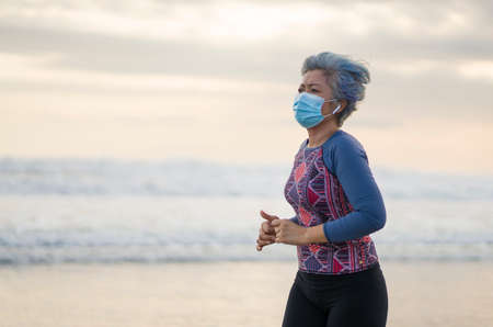 new normal running workout with face mask - attractive and happy middle aged woman on her 40s or 50s...