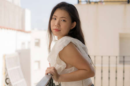 lifestyle portrait of young attractive and beautiful Asian Chinese woman outdoors at urban balcony in Spain enjoying summer holidays travel happy and carefreeの写真素材