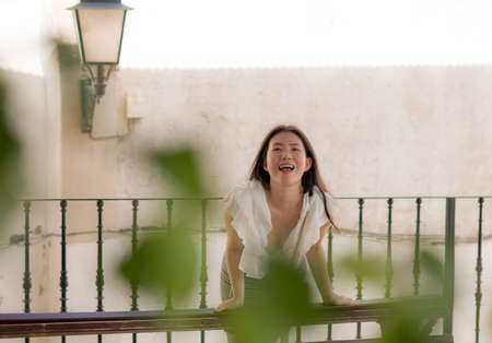 lifestyle portrait of young attractive and beautiful Asian Chinese woman outdoors at urban balcony in Spain enjoying summer holidays travel happy and carefreeの写真素材