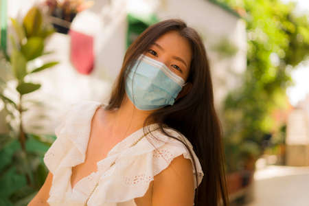 new normal tourism and travel - young happy and beautiful Asian Chinese woman in face mask visiting Seville in Spain enjoying Europe Summer holiday relaxed during city tourの写真素材