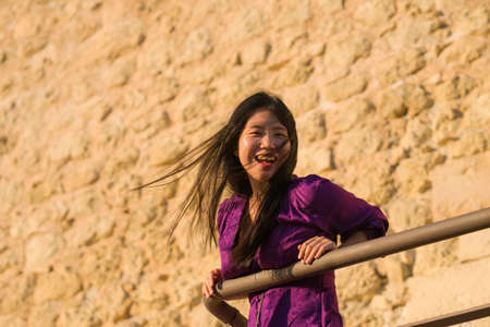 young happy and beautiful Asian Korean woman outdoors at viewpoint balcony enjoying sunset view of Spain town during Europe holiday travel feeling free and relaxedの写真素材
