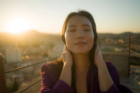 young happy and beautiful Asian Korean woman outdoors at viewpoint balcony enjoying sunset view of...