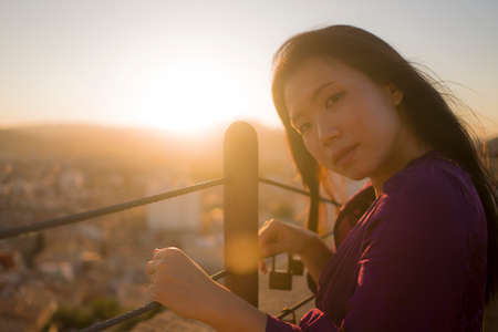 young happy and beautiful Asian Korean woman outdoors at viewpoint balcony enjoying sunset view of...