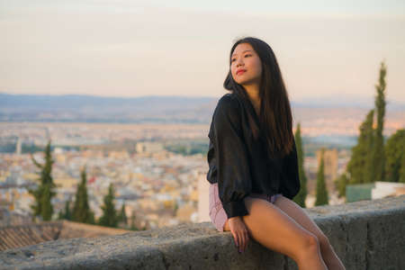 lifestyle portrait of young beautiful and happy Asian Japanese tourist woman having Summer holidays in Europe enjoying cheerful visiting beautiful Alhambra of Granada in Spainの写真素材