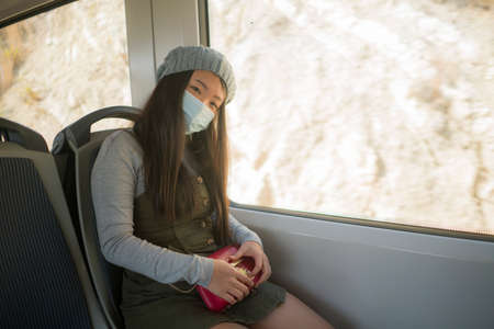 new normal traveling - young attractive and pretty Asian Korean woman in face mask sitting on railcar by window enjoying trip in the train relaxed and thoughtfulの写真素材
