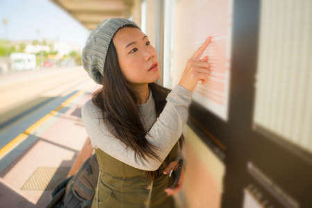 outdoors lifestyle portrait of young beautiful and happy Asian Chinese woman waiting the train on...