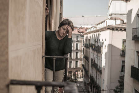 dramatic lifestyle portrait of mature woman on her 70s crying depressed and sad at home balcony feeling desperate suffering anxiety problem in senior female depression conceptの写真素材