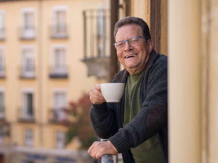 lifestyle portrait of happy and cheerful mature man 65 to 70 years old at home balcony feeling...