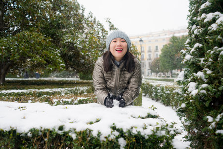 lifestyle portrait of  young happy and attractive Asian Korean woman in winter hat and mask at...