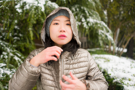 lifestyle portrait of  young happy and attractive Asian Korean woman in winter hat and mask at...