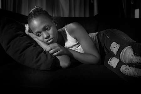 teen African American girl at night suffering depression - dramatic artistic portrait of young attractive sad and depressed black woman worried and upset alone in the darkの写真素材