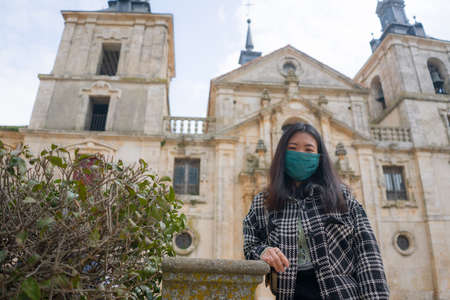 tourism and travel in times of - young happy and beautiful Asian Korean woman in surgical mask vs enjoying city tour during holidays in Europeの写真素材