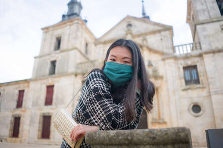 tourism and travel in times of - young happy and beautiful Asian Korean woman in surgical mask   enjoying city tour during holidays in Europeの写真素材
