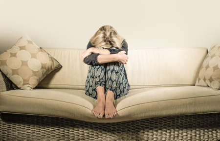 beautiful 40s woman depressed at home - dramatic portrait of sad and desperate blonde girl on couch suffering depression problem and anxiety crisis feeling helpless and lonelyの写真素材