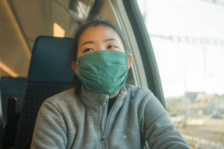 train travel during covid19 - young happy and cute Asian Japanese woman in  face mask traveling on railcar enjoying landscape through the windowの写真素材