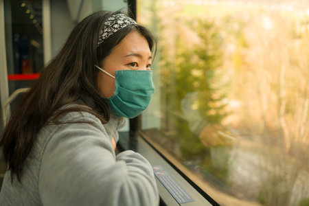 train travel in times of covid19 - young happy and cute Asian Chinese woman in  face mask traveling...