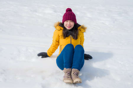 Winter holidays in the snow - lifestyle portrait of young happy and beautiful Asian Chinese girl enjoying playful at frozen lake in snowy mountains at Swiss Alpsの写真素材