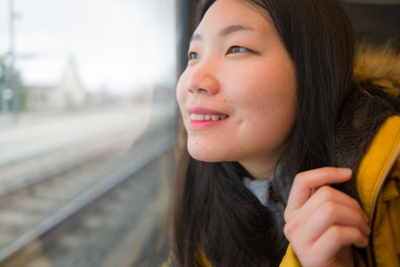 young beautiful and happy Asian Korean woman sitting on train looking out to window enjoying holidays travel in Europe smiling thoughtful and sweetの写真素材