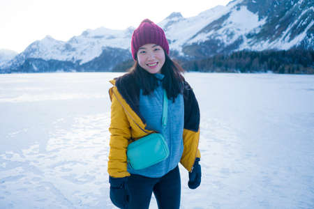 lifestyle portrait of young happy and beautiful Asian Chinese woman in winter jacket and beanie...