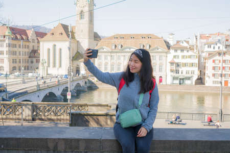 Asian woman backpacker touring in Europe - young happy and pretty Korean girl with student backpack...