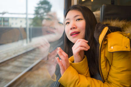 young beautiful and happy Asian Chinese woman sitting on train looking out to window enjoying holidays travel in Europe smiling thoughtful and sweetの写真素材