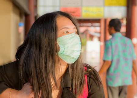 travel and holiday in times of covid-19 - young pretty Asian Chinese woman with backpack waiting at airport departure wearing protective mask against covid19 virusの写真素材