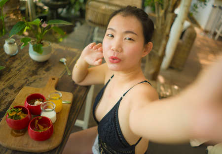 summertime lifestyle portrait of young attractive and happy Asian Korean woman taking selfiei having...