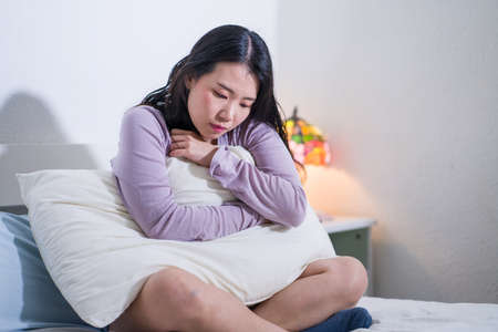 young Asian woman depressed - young beautiful and sad  Korean girl on bed with pillow feeling unhappy and broken heart suffering depression problem at home bedroomの写真素材