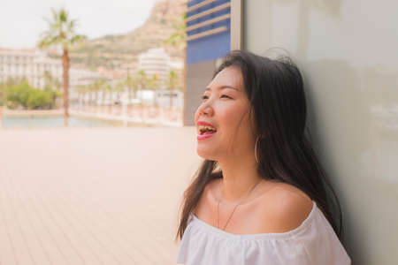 young happy and attractive Asian woman outdoors - natural portrait of beautiful Korean girl enjoying sunny day in white Summer dress smiling cheerfulの写真素材