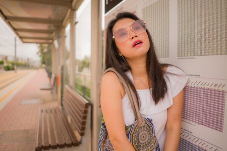 young beautiful Asian woman waiting for train - lifestyle portrait of attractive and happy Chinese...