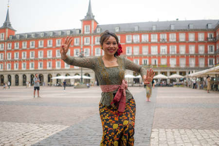 young happy and beautiful Asian woman wearing traditional Balinese kebaya dress - Indonesian girl doing Bali dance on street during holidays travel in Europeの写真素材