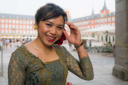 young happy and beautiful Asian woman wearing traditional Balinese kebaya dress - Indonesian girl in Bali clothes walking on street during holidays travel in Europeの写真素材