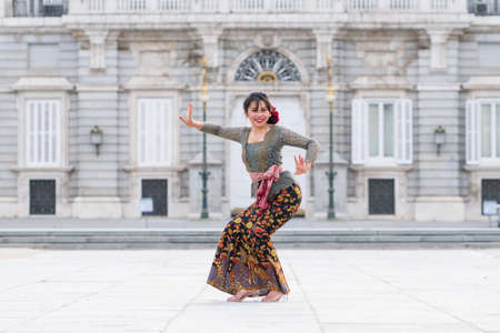 young happy Indonesian woman from Bali having vacation in Europe - beautiful and exotic Balinese tourist girl dancing in traditional outfit touring in the city enjoying holidaysの写真素材