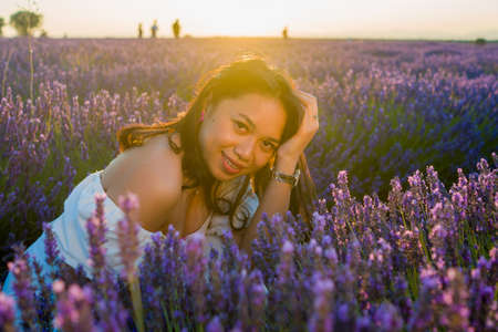 outdoors romantic portrait of young happy and attractive woman in white summer dress enjoying carefree at beautiful lavender flowers field in travel and holiday conceptの写真素材