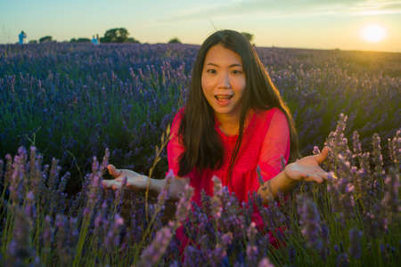young happy and beautiful Asian Korean woman in Summer dress enjoying free and playful at purple lavender flowers field on sunset in romantic beauty and freedom conceptの写真素材