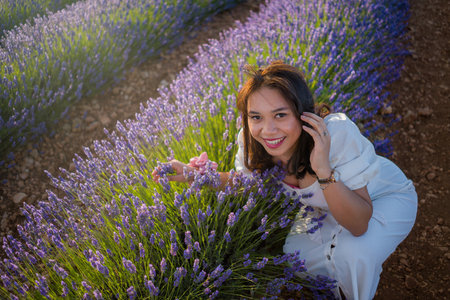 outdoors romantic portrait of young happy and attractive woman in white summer dress enjoying carefree at beautiful lavender flowers field in travel and holiday conceptの写真素材