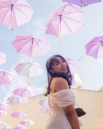 outdoors urban lifestyle portrait of young happy and attractive woman on street full of hanging umbrellas during summer holidays travel in Europeの写真素材