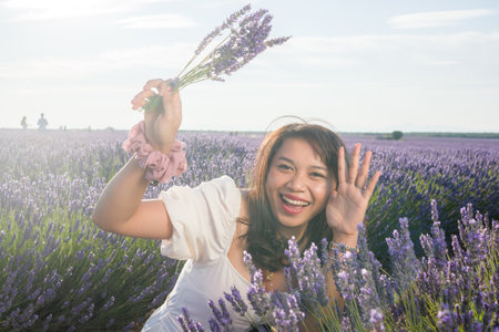 outdoors romantic portrait of young happy and attractive woman in white summer dress enjoying carefree at beautiful lavender flowers field in travel and holiday conceptの写真素材