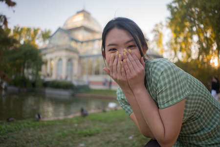 lifestyle portrait of young happy and attractive Asian Chinese woman relaxed taking a walk on city park enjoying travel getaway in Spain during Autumn holidays travelの写真素材